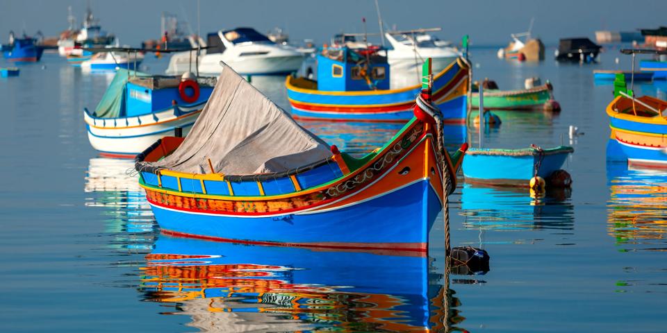 Traditional eyed colorful boats Luzzu in the Harbor of Mediterranean fishing village Marsaxlokk, Malta