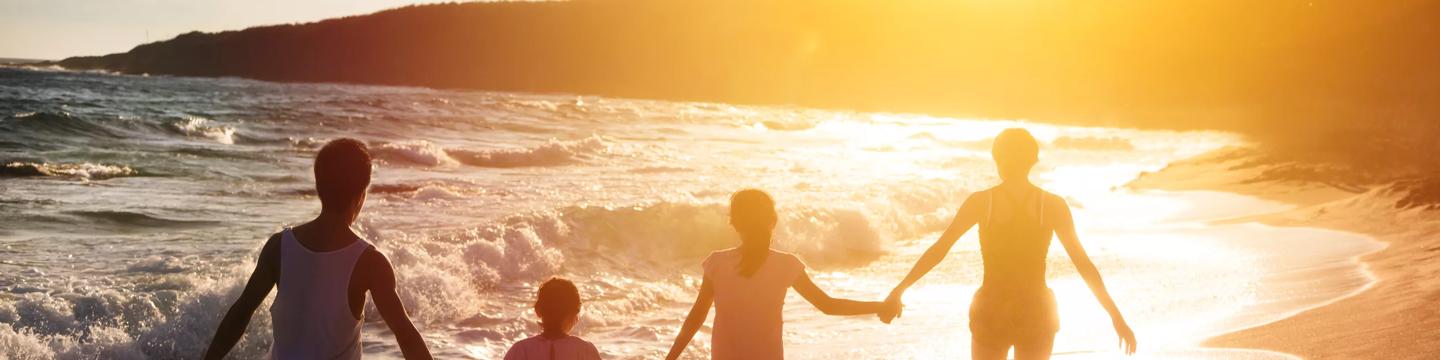 family holding hands from behind on the beach